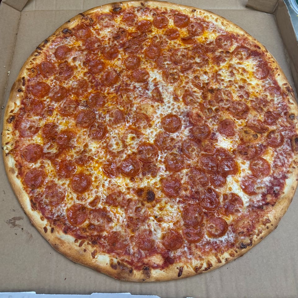 A large, round pepperoni pizza with melted cheese and a golden crust in a cardboard box.