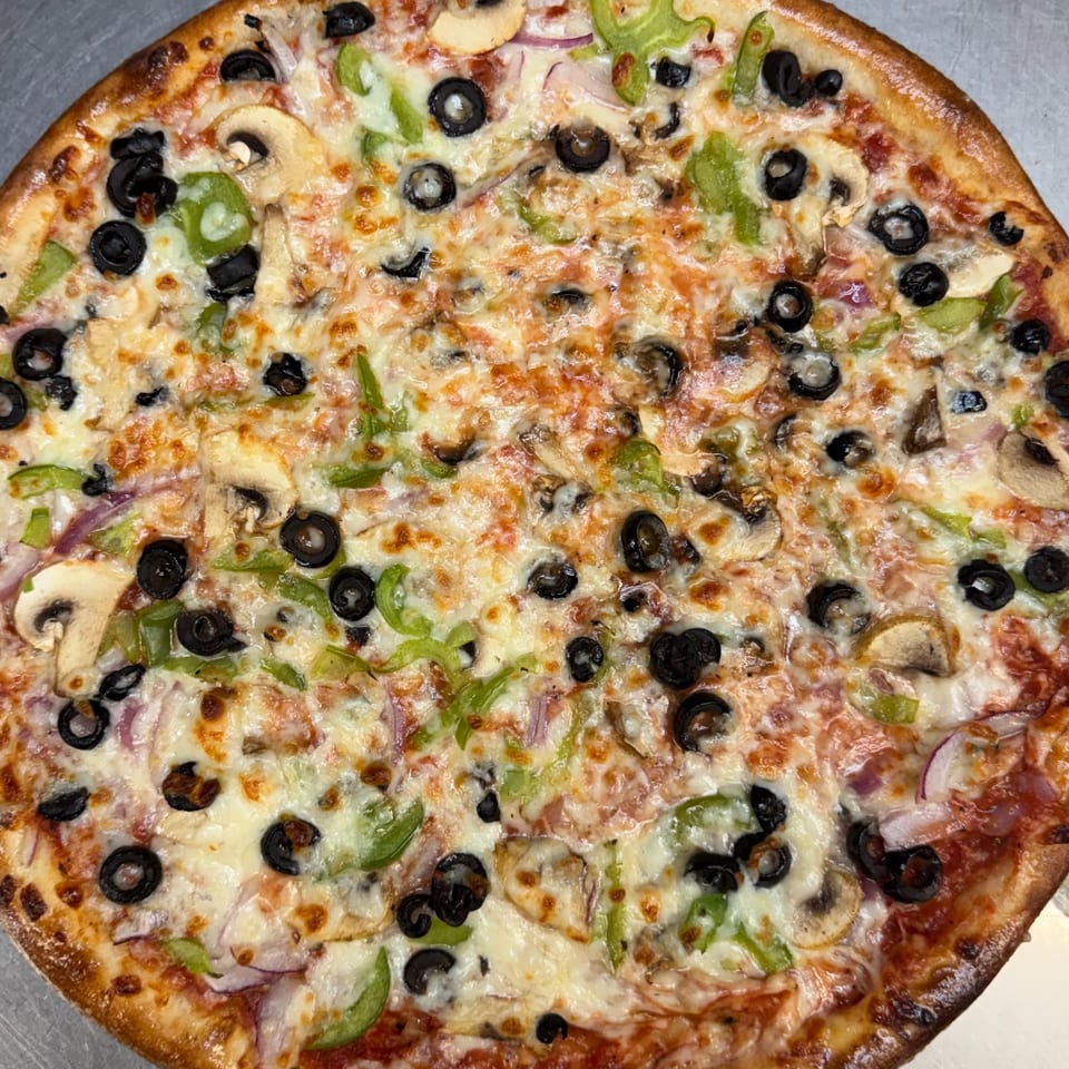 A close-up of a freshly baked pizza topped with melted cheese, black olives, green peppers, and mushrooms.